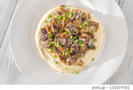 Braised meat and mushroom topping over creamy mashed potato served on white plate 131874501