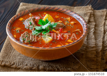 Rustic clay bowl filled with traditional Hungarian Bogracs stew on wooden table Rustic clay bowl filled with traditional Hungarian Bogracs stew on wooden table 131874510
