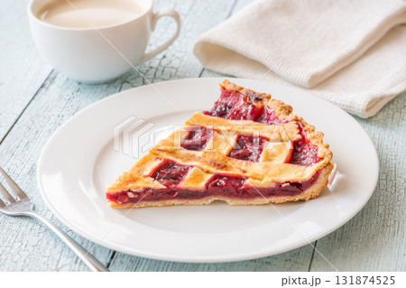 Wedge of cherry pie with coffee and fork on bright rustic table Wedge of cherry pie with coffee and fork on bright rustic table 131874525