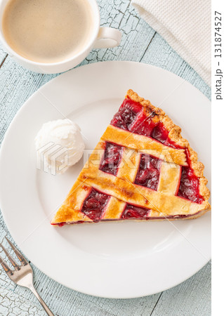 Cherry pie slice with melting ice cream and coffee on white plate 131874527