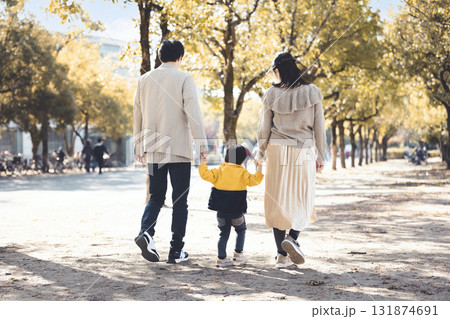 秋の公園で並木道を手をつないで歩く仲良し家族 131874691