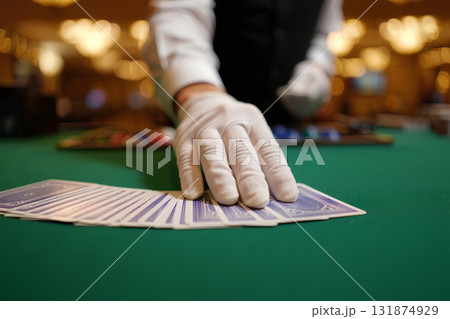 Close-up of casino dealer's hands laying out playing cards on the green felt table, poker or blackjack game in session Close-up of casino dealer's hands laying out playing cards on the green felt table, poker or blackjack game in session 131874929