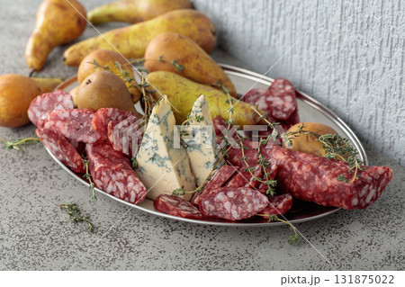 Blue cheese, dry-cured sausages, thyme and pears on a stone table. Blue cheese, dry-cured sausages, thyme and pears on a stone table. 131875022