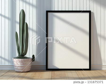 A tall cactus in a pink planter stands next to a large, blank black frame against a white paneled wall, with strong sunlight and shadows cast across the scene. A tall cactus in a pink planter stands next to a large, blank black frame against a white paneled wall, with strong sunlight and shadows cast across the scene. 131875371