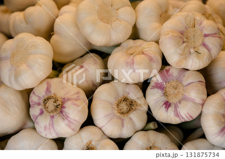 Fresh garlic bulbs arranged in bulk at a market stall, representing organic farming, natural Fresh garlic bulbs arranged in bulk at a market stall, representing organic farming, natural 131875734