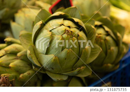 Fresh green artichoke photographed closeup at a market stall, symbolizing organic farming, healthy Fresh green artichoke photographed closeup at a market stall, symbolizing organic farming, healthy 131875735
