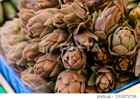 Fresh artichokes arranged in a pile at a market stall, symbolizing organic farming, seasonal harvest 131875736