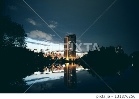 A city building built on the shore of a reservoir at night 131876256