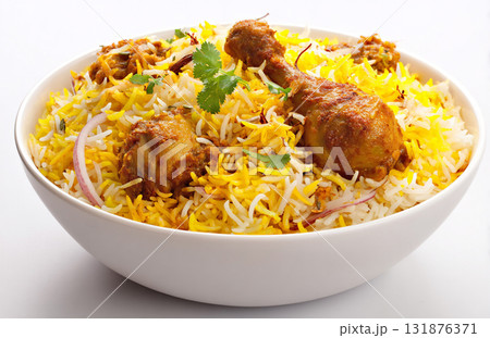 A close-up of delicious Chicken Biryani in a bowl, featuring spiced chicken pieces, basmati rice, saffron color, onions, and cilantro. 131876371