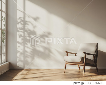 An empty, sunlit room with a modern wooden armchair, featuring strong geometric shadows. 131876600