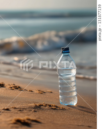 Clear plastic water bottle blue cap beach sand ocean wave morning sunlight reflective condensation 131877139
