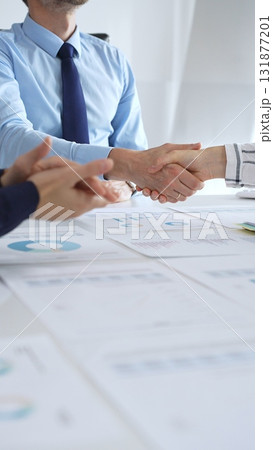 Business partnership success concept with handshake in modern office, financial charts, graphs and laptop on desk representing teamwork, agreement and corporate growth 131877201