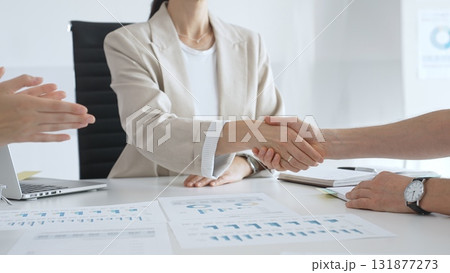 Businesspeople dressed in casual style are shaking hands, confirming partnership agreement while sitting in contemporary corporate sunny office. Business handshake concept 131877273