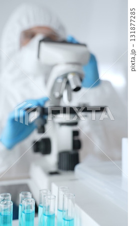 Scientific researcher wearing blue protective gloves fine tuning microscope lenses during medical laboratory investigation. Medicine, healthcare and science concept 131877285
