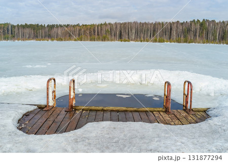A wooden dock surrounded by melting ice on a lake. Ice hole for swimming in winter A wooden dock surrounded by melting ice on a lake. Ice hole for swimming in winter 131877294