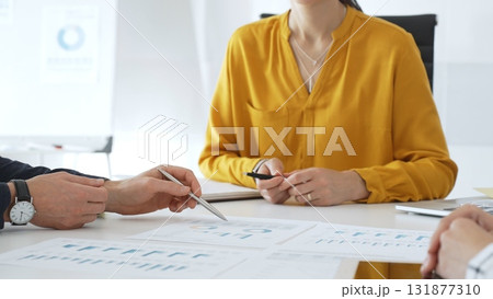 Business professionals gathered around conference table, reviewing financial charts, collaborating on strategic planning and corporate analysis 131877310