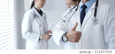 Doctor giving thumbs up sign for medical approval while standing with health practitioners, symbolizing trust in healthcare, patient well being, and successful treatment Doctor giving thumbs up sign for medical approval while standing with health practitioners, symbolizing trust in healthcare, patient well being, and successful treatment 131877505