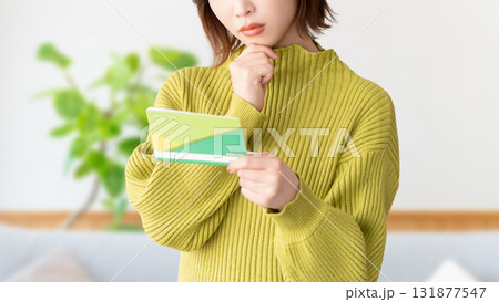 通帳を見て考える女性 131877547