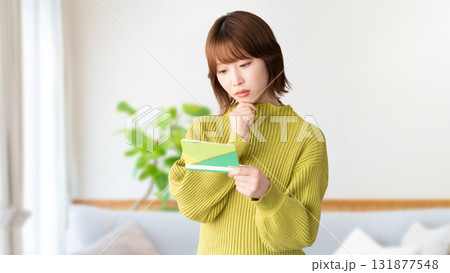 通帳を見て考える女性 通帳を見て考える女性 131877548