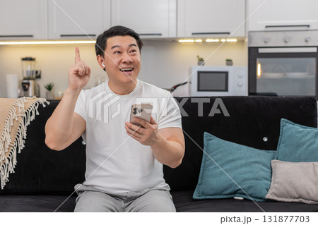 Asian man studies online course on smartphone in headphones finds solution shows ok sign sets goal Asian man studies online course on smartphone in headphones finds solution shows ok sign sets goal 131877703