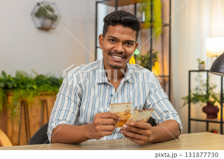 Indian man counts euro cash bonus salary plans invest smiles proud income wealth profit success joy Indian man counts euro cash bonus salary plans invest smiles proud income wealth profit success joy 131877730