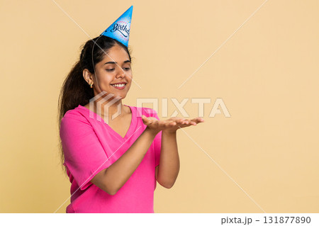 Indian woman smiling holding imaginary cake, joyfully blowing candle, happily making birthday wish Indian woman smiling holding imaginary cake, joyfully blowing candle, happily making birthday wish 131877890