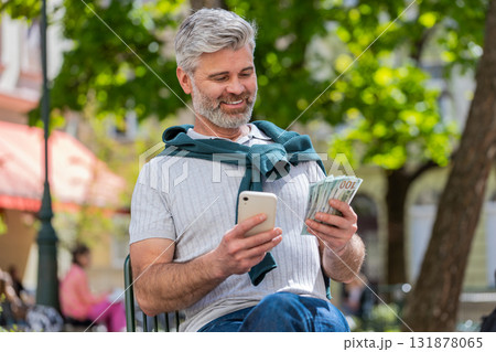 Happy rich mature man counting holding money dollar cash use smartphone calculator app booking hotel 131878065