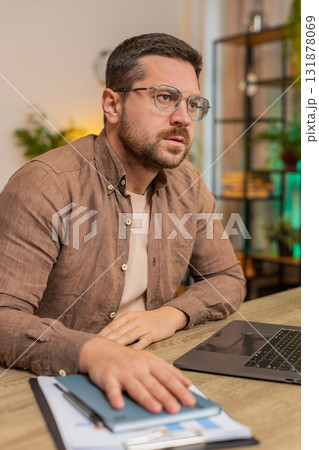 Sad Caucasian young man freelancer looks pensive thinks over life concerns sitting at desk at home 131878069