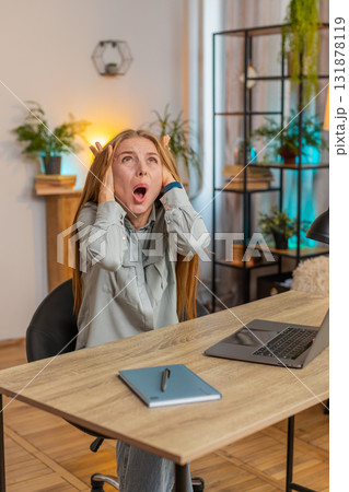 Frustrated freelancer using laptop struggling to work due to loud noise sitting at home office table Frustrated freelancer using laptop struggling to work due to loud noise sitting at home office table 131878119