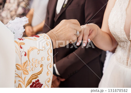 Orthodox Wedding Ceremony Ring Exchange: Priest, Bride, Groom, White Dress, Hands, Faith, Symbolism, Celebration, Gold, Elegant, Traditional 131878582