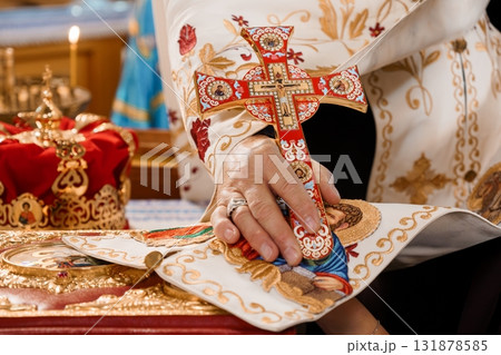 Eastern Orthodox Priest Holding Red Cross During Religious Ceremony, Gold Vestments, Church Interior, Spiritual Faith. 131878585