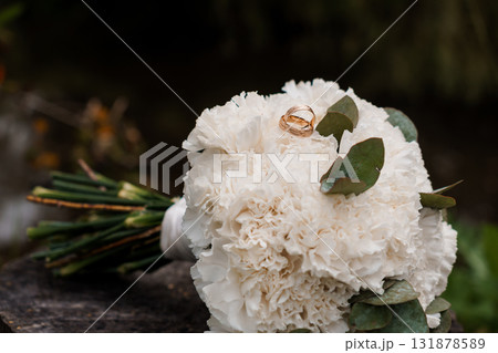 Wedding Rings on White Carnation Bouquet, Rustic Love, Close-Up Photography, Soft Focus, Romantic Engagement, Floral Arrangement, Natural Light. 131878589