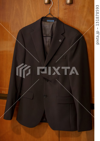 Brown Men's Suit Hanging in Wardrobe. Fashion, Formal Wear, Closet, Chocolate Color, Professional Style, Business Attire, Textile Texture. Brown Men's Suit Hanging in Wardrobe. Fashion, Formal Wear, Closet, Chocolate Color, Professional Style, Business Attire, Textile Texture. 131878593