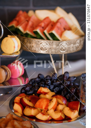 Sumptuous Fruit Platter Display with Macarons and Grapes on Silver Trays, Dark Moody Table Setting 131878647