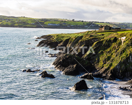 Scenic ocean view with old building. Green cliffs by the shore. 131878713