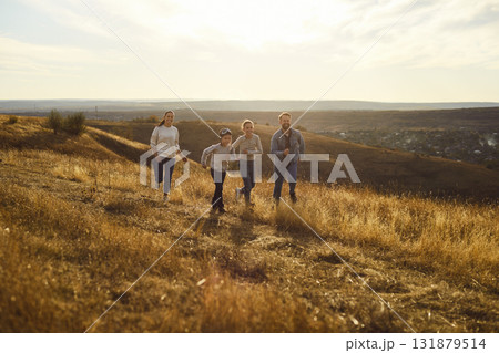 Positive happy family running outdoors, feeling free and relaxed in nature, posing on meadow Positive happy family running outdoors, feeling free and relaxed in nature, posing on meadow 131879514