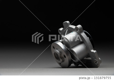 A new, shiny aluminum engine coolant pump on a gray gradient background. Contrast backlighting. 131879755