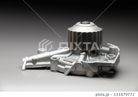 A new, shiny aluminum engine coolant pump on a gray gradient background. Contrast backlighting. 131879772