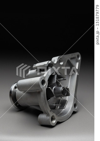 A new, shiny aluminum engine coolant pump on a gray gradient background. Contrast backlighting. 131879779