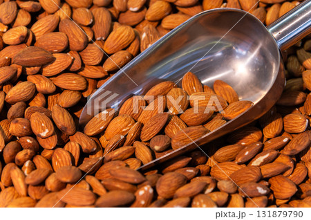 Metal scoop surrounded by almonds raw. Close-up. Background for snacks and nuts Metal scoop surrounded by almonds raw. Close-up. Background for snacks and nuts 131879790