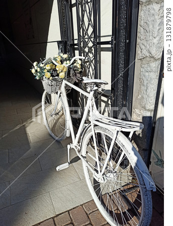 white decorative bicycle with flowers  in busket  on enter to shop. sunny day 131879798