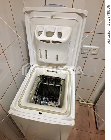 Top-loading washing machine with the open lid stands in the bathroom 131879936
