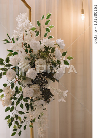 Elegant floral wedding decoration with white roses and greenery on beige curtain background 131880161