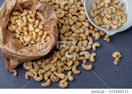 Paper bag and bowl of cashew nuts on gray background 131880211