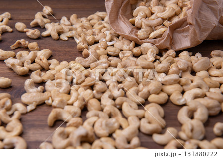 cashew nuts on wooden background. cashew in paper bag. cashew nuts on wooden background. cashew in paper bag. 131880222