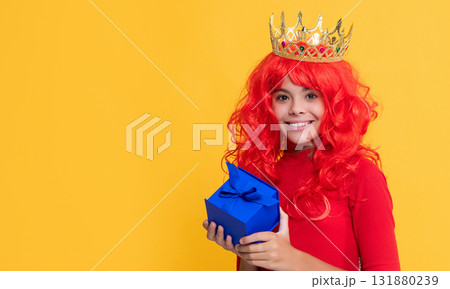 positive girl in crown with present box on yellow background positive girl in crown with present box on yellow background 131880239