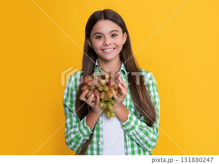 positive child with grapes bunch on yellow background. vitamins positive child with grapes bunch on yellow background. vitamins 131880247
