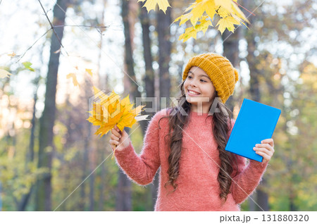 Outdoor learning fun for the autumn months. Happy child hold book and autumn leaves. Back to school. Reading education. Knowledge day. Exploring and learning about nature in fall Outdoor learning fun for the autumn months. Happy child hold book and autumn leaves. Back to school. Reading education. Knowledge day. Exploring and learning about nature in fall 131880320