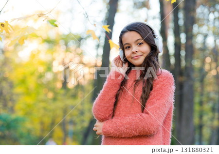 Confident in style. fall is a time for study. back to school. concept of online education. child in sweater enjoy listening ebook. new technology. girl in earphones. kid listen music in autumn park 131880321