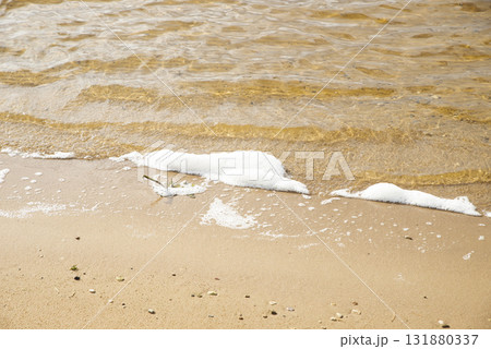 Polluted water with foam and debris flows next to muddy banks, showing environmental degradation. The murky liquid and dirty surroundings highlight the impact of contamination 131880337